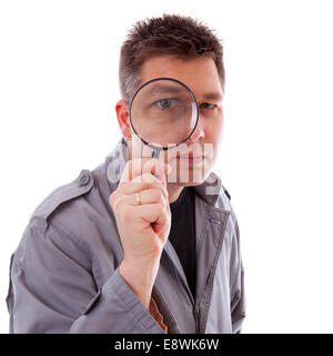Man with raincoat is looking through magnifying glass and has a big eye over white background Stock Photo