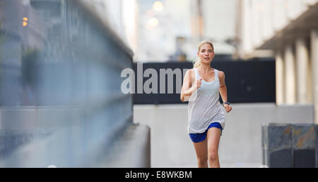 Woman running through city streets Stock Photo