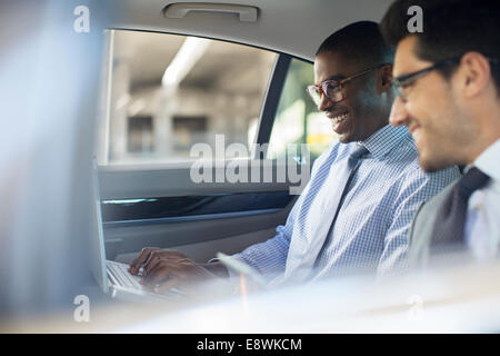 Businessmen using laptop in car Stock Photo