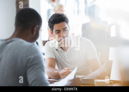 Businessmen looking through documents in cafe together Stock Photo