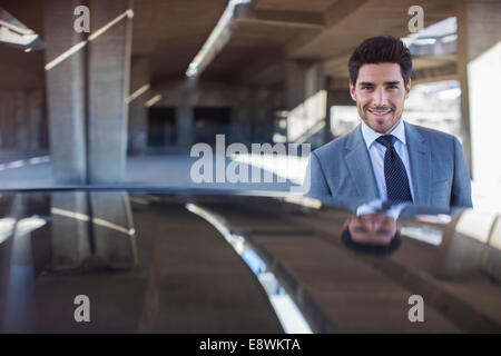 Businessman standing near car in parking garage Stock Photo