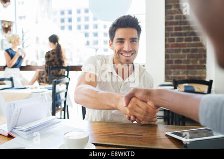 Businessmen shaking hands in cafe Stock Photo