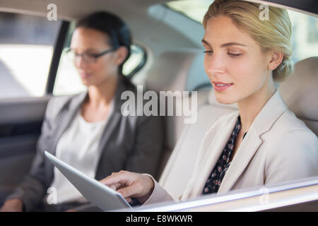 Businesswoman using digital tablet in car back seat Stock Photo