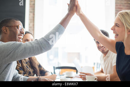 Business people high fiving at meeting in cafe Stock Photo
