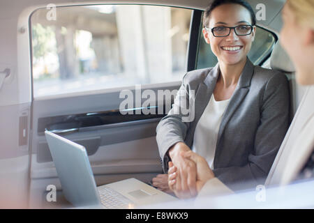 Businesswomen shaking hands in car Stock Photo