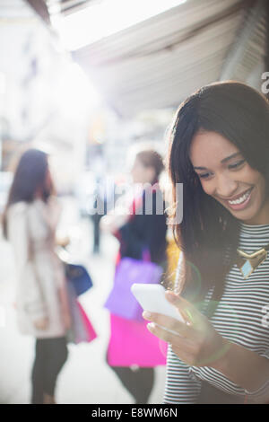 Woman using cell phone on city street Stock Photo
