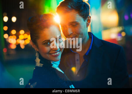 Couple hugging on city street at night Stock Photo