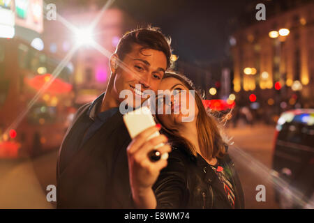 Couple taking picture together with cell phone at night Stock Photo