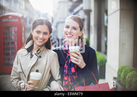 Women drinking coffee together down city street Stock Photo