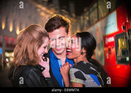 Friends hugging on city street at night Stock Photo