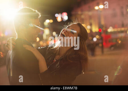 Couple hugging on city street at night