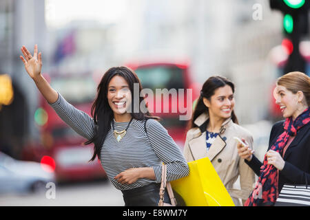 Woman calling taxi with friends on city street Stock Photo