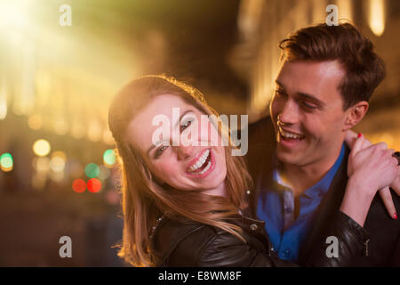 Couple hugging on city street at night