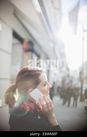 Woman talking on cell phone on city street Stock Photo