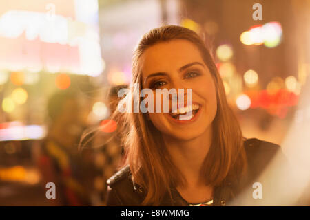 Woman smiling on city street at night Stock Photo