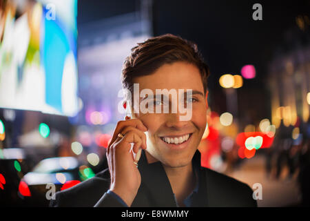 Man talking on cell phone on city street at night Stock Photo