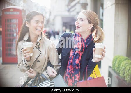 Women drinking coffee together on city street Stock Photo