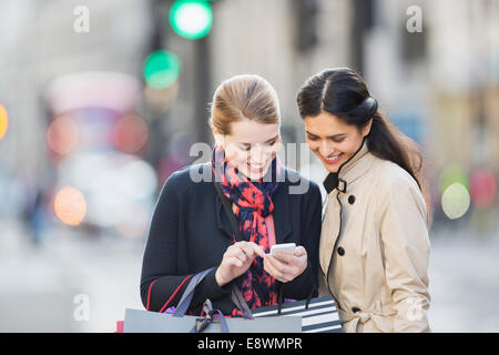 Women looking at cell phone on city street Stock Photo