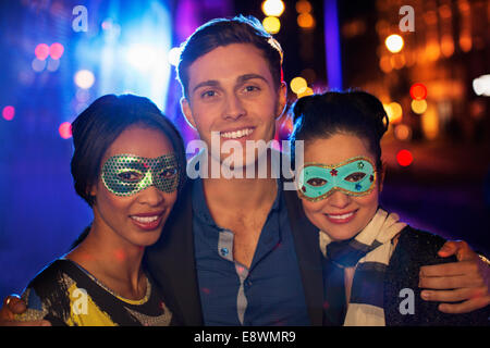 Friends smiling together on city street at night Stock Photo