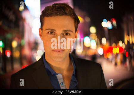 Man smiling on city street at night Stock Photo