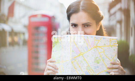 Woman holding map on city street Stock Photo
