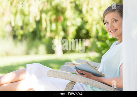 Woman reading book in lawn chair outdoors Stock Photo