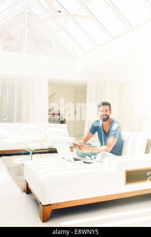 Man using laptop on sofa in modern living room Stock Photo