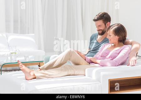 Couple using laptop on sofa in modern living room Stock Photo