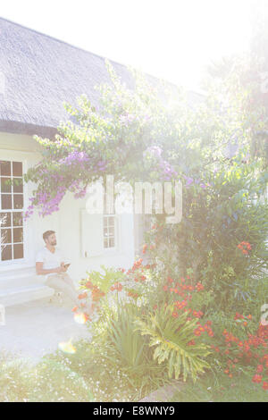 Man on porch admiring flowers in backyard Stock Photo