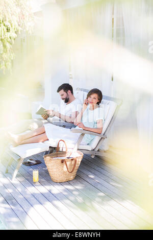 Couple relaxing in lawn chairs on wooden deck Stock Photo