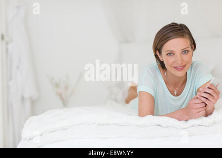 Woman using cell phone on bed Stock Photo