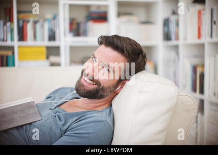 Smiling man listening to music on sofa Stock Photo
