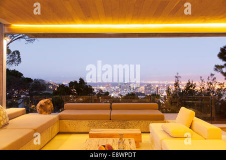 Modern living room overlooking illuminated cityscape at night Stock Photo