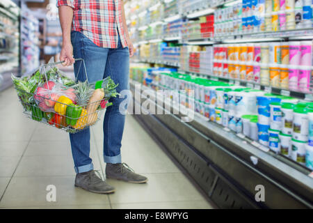 Man carrying full shopping basket in grocery store Stock Photo