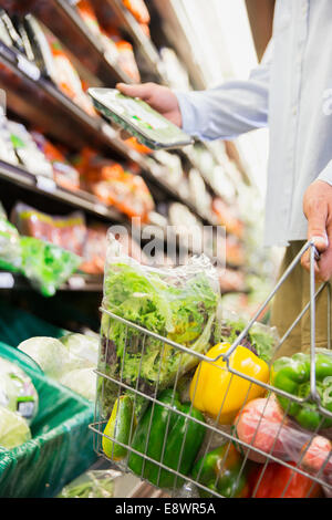 Close up of man holding full shopping basket in grocery store Stock Photo