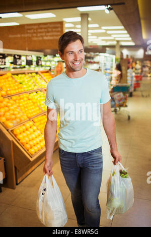 Man carrying shopping bags in grocery store Stock Photo