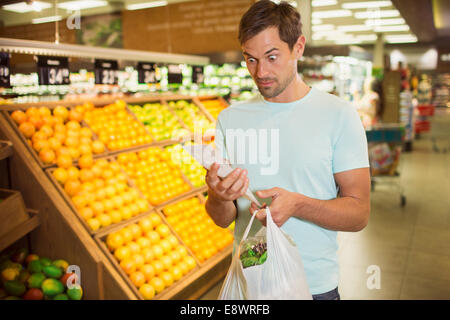 Surprised man reading receipt in grocery store Stock Photo