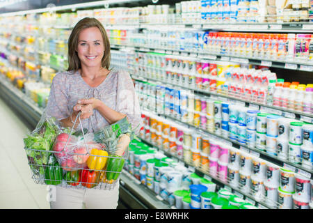Woman carrying full shopping basket in grocery store Stock Photo