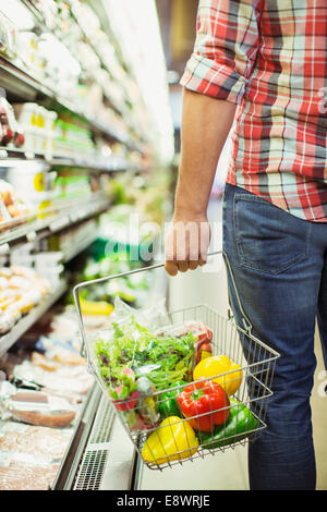 Man carrying full shopping basket in grocery store Stock Photo