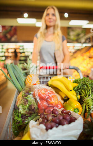 Woman pushing full shopping cart in grocery store Stock Photo