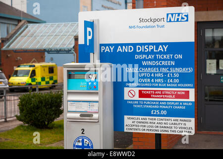 Pay and Display meter to issue tickets, and charges / parking charging rate sign, in an NHS hospital Car Park. UK Stock Photo