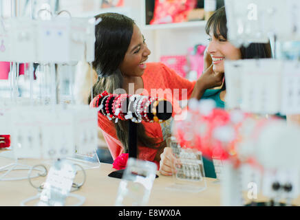 Women trying on jewelry together in clothing store Stock Photo
