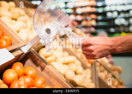 Close up of man taking plastic bag in produce section of grocery store Stock Photo