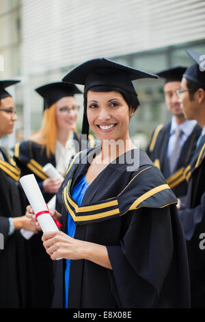 Student in cap and gown standing with friends Stock Photo