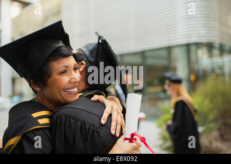 Students in cap and gown hugging Stock Photo