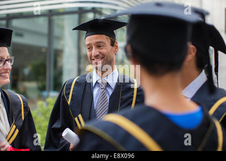 Students in cap and gown talking Stock Photo