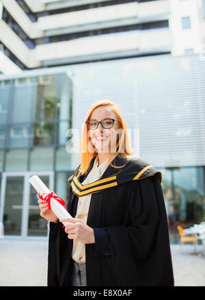 Student in cap and gown holding scroll Stock Photo