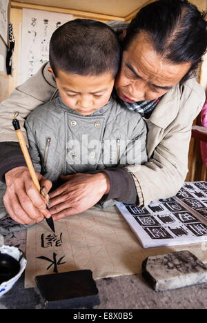 Teacher and pupil at traditional calligraphy school. Lijiang, China Stock Photo