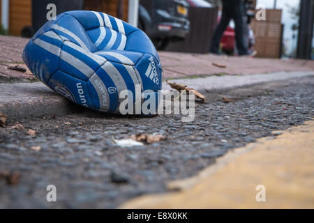 deflated football in the gutter Stock Photo