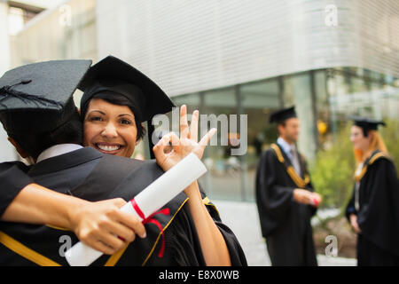 Students in cap and gown hugging Stock Photo